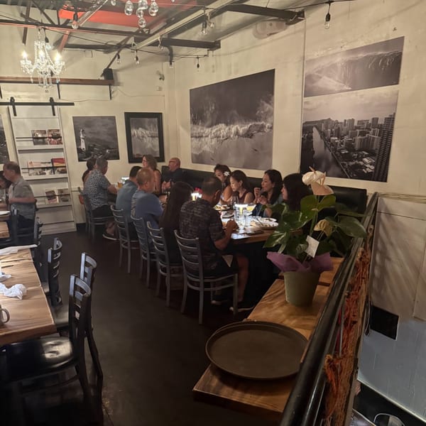 Diners seated at long tables in The Surfing Pig restaurant, with large black and white art on walls.