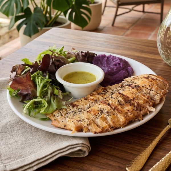 Grilled chicken, purple mashed potatoes, and a side salad with dressing on a white plate.